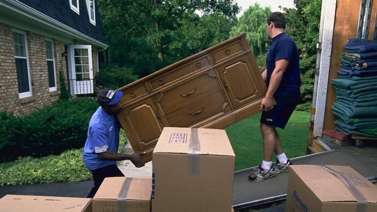 Professional movers loading a wooden dresser into a moving truck during Furniture Removal Kent WA service at a residential home.